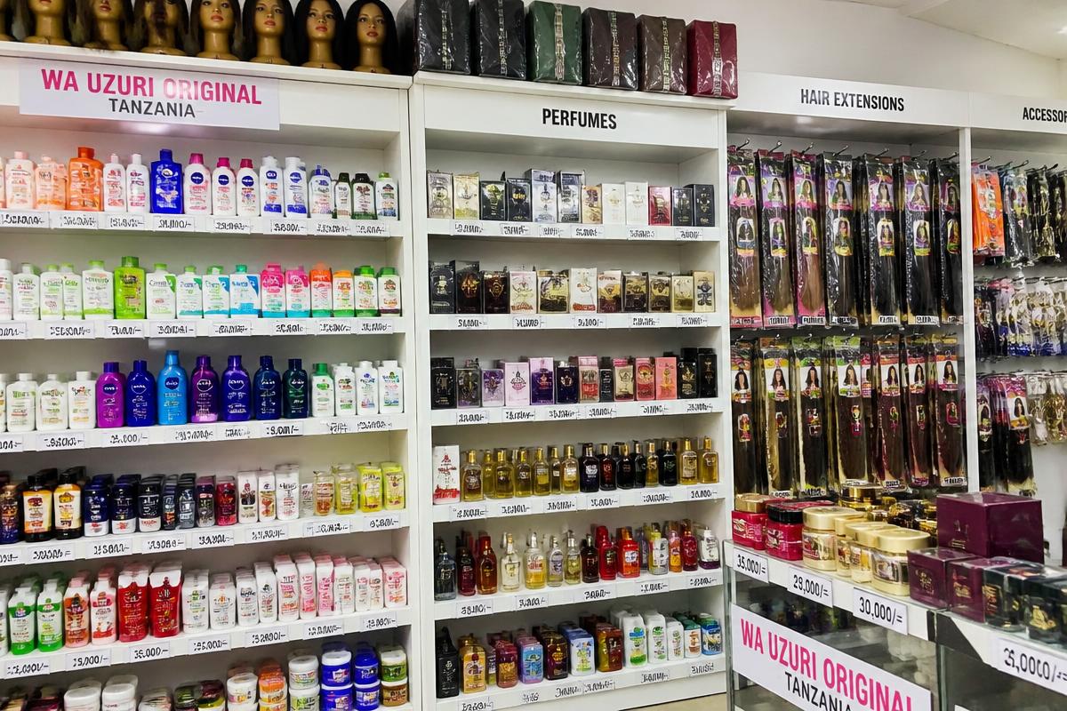 Shelves of perfumes, skincare and hair extensions with price labels in a Tanzanian beauty supply store